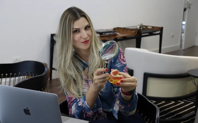 Dra. Jéssica analisando um modelo odontológico com lupa