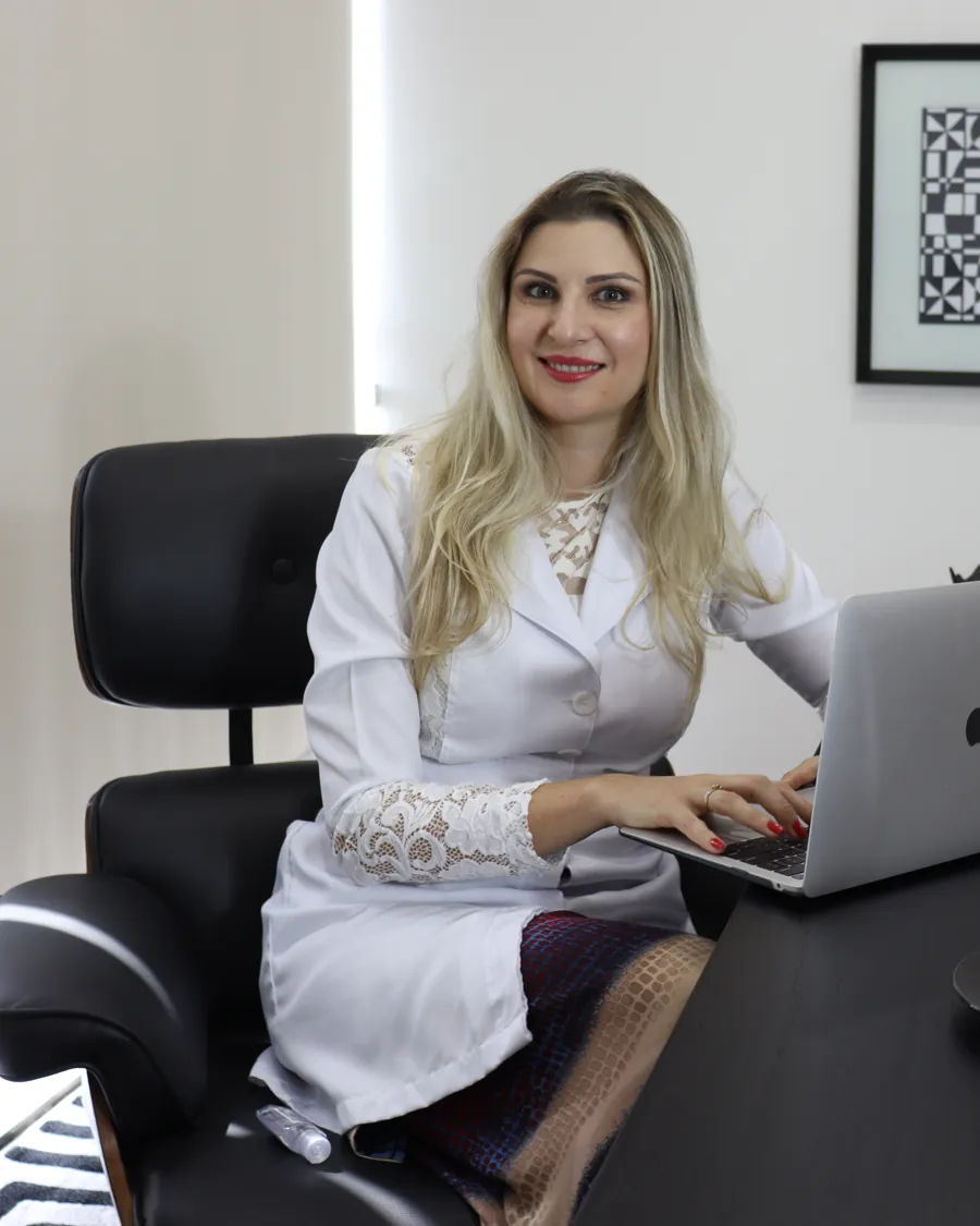 Dra. Jéssica da Silva Pinto, de jaleco, em seu escritório